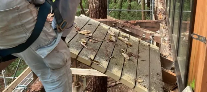 屋外で壁を部分的に解体している作業員
